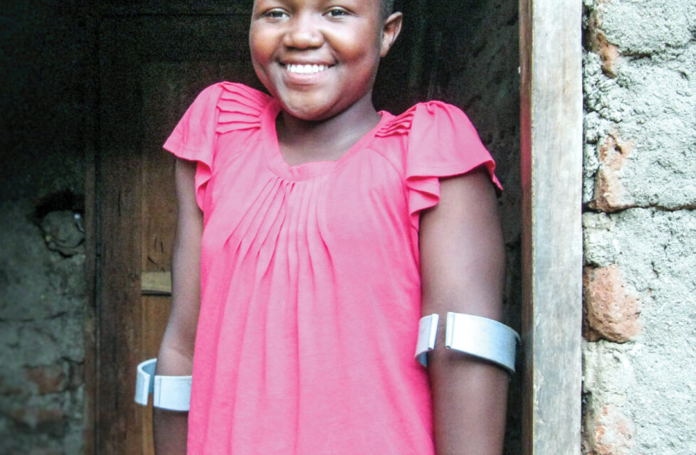 a young girl stands in a door way with crutches smiling